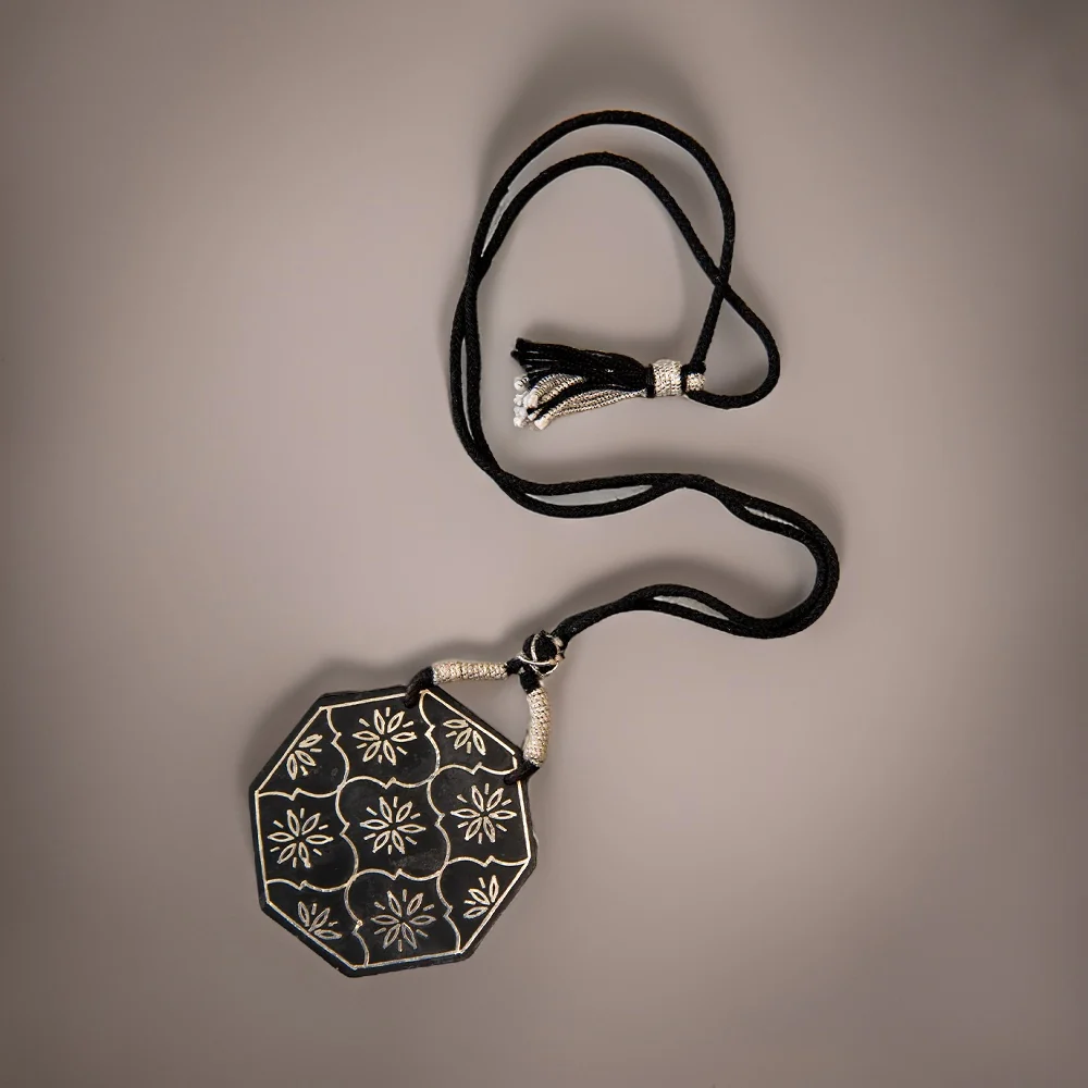 Close view of hand-engraved silver inlay pattern on a Bidri pendant
